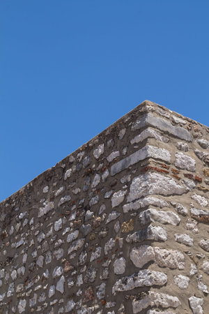 View from down on the corner of a wall - fence made of stones. Bright blue sky. Cacela Velha,...