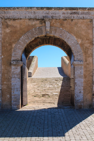 Historical heritage, portuguese fortress on the coast of Atlantic ocean. Door in the fortification wall. Bright blue sky. El Jadida, Morocco.の写真素材
