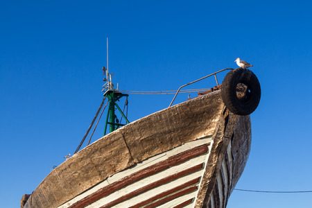 Wooden fishing boat out of the Atlantic ocean water, parked on the shore. Bright bue morning sky. Old original port in Essaouira, Morocco.の写真素材
