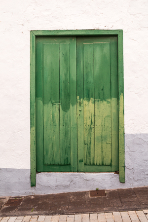 Characteristic green color of the details and gates of the houses. Old peeled of color, creating a texture. White facade of the house. Arico Nuevo, Tenerife, Canary Islands, Spain.の写真素材