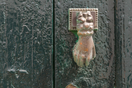 Wooden gate painted green, which is traditional color of the area. Old brass door knob in a shape of a hand. Arico Nuevo, Tenerife, Canary Islands, Spain.の写真素材