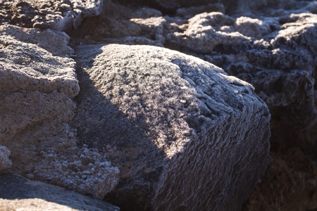 Thin layer of the frost on the lava stones in the cold spring morning in Teide National Park, creating various structure, enlightened by the sun. Tenerife, Canary Islands, Spain.の写真素材