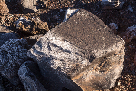 Thin layer of the frost on the lava stones in the cold spring morning in Teide National Park, creating various structure, enlightened by the sun. Tenerife, Canary Islands, Spain.の写真素材