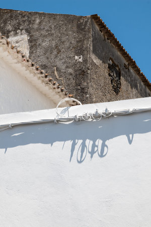 Bright blue fence with a shadow of the cables. Old house in the background, with an edge of the...