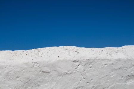 Rough surface of a bright white fence. Bright blue sky. Estoi, Portugal.の写真素材