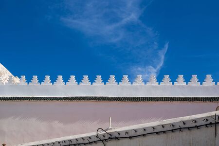 Horizontal and diagonal lines of buildings in the old downtown (medina). Bright blue sky with a light touch of a white cloud. Essaouira, Morocco.の写真素材