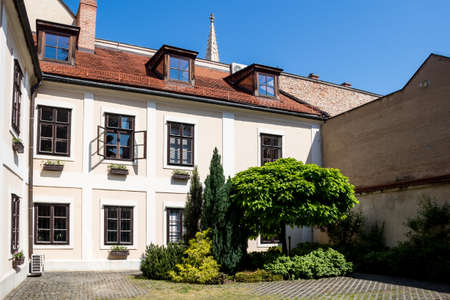 Inner yard of a renewed historical buidling in the downtown. Group of trees and bushes. Bright blue sky. Bratislava, Slovakia.のeditorial素材