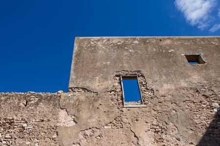 Walls without a facade and holes instead of windows. Ruins of abandoned house. Bright blue sky. Dar Caid Hadji (used also Hajji), Morocco.の写真素材