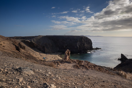 View from the mountain on Papagayo Beach. Atlantic ocean in a late afternoon light. Clouds on a blue sky in the early spring. Playa del Papagayo, Lanzarote, Canary Islands, Spain.の写真素材