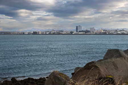 Coast of the North Atlantic ocean in the harbor. Cityview with an intense cloudy sky. Extremely windy day created waves. Port of Reykjavik, Iceland.の写真素材