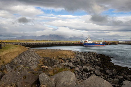 Coast of the North Atlantic ocean in the harbor. Cityview with an intense cloudy sky. Extremely windy day created waves. Port of Reykjavik, Iceland.の写真素材