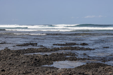 Rocky beach on the north of the island. Waves of Atlantic ocean in the winter. Blue sky with very...