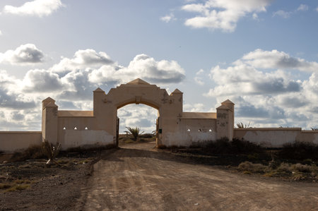 Traditional style of spanish architecture: decorative gate with fence. Gravel road. Cloudy sky. Centre of the island, near Tindaya. Fuerteventura, Canary Islands.の写真素材