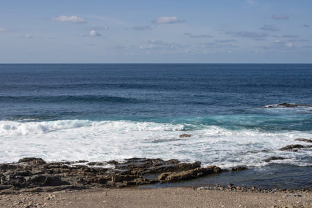 Beach of the Atlantic ocean with a rocky coast. Calm water in the winter. Blue sky with light...