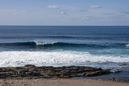 Beach of the Atlantic ocean with a rocky coast. Calm water in the winter. Blue sky with light...