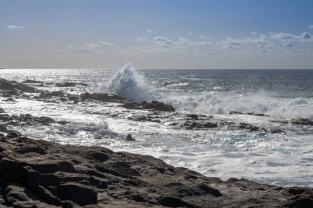 Beach of the Atlantic ocean with a rocky coast. Calm water in the winter. Blue sky with light...