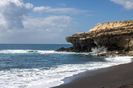 Atlantic ocean beach on the west of the island. Rythm of the cliffs. Calm water. Blue sky with white clouds. Ajuy, Fuerteventura, Canary Islands, Spain.の写真素材