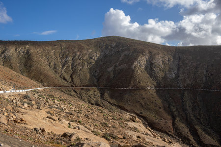 High mountains in the centre of the island, with a small line of a road. Intense clouds. Mirador del Risco de las Penas, Betancuria, Fuerteventura, Canary Islands, Spain.の写真素材