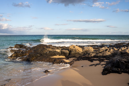 Combination of a sand and rocky coast at the beach of Atlantic ocean. Blue sky with white clouds. Parque Natural Dunas de Corralejo, Fuerteventura, Spain.の写真素材