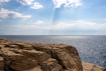 Details of structure of a limestone rock above the sea. Thracian sea (Mediterranean) with its horizon. Blue sky with white clouds and rays of sunshine. Giola lagoon, Thassos (Tassos), Greece.の写真素材