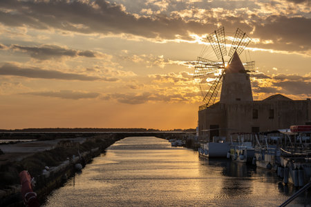 Salt pans and windmills for processing the sea salt. Channel among them. Cloudy sky in the spring...