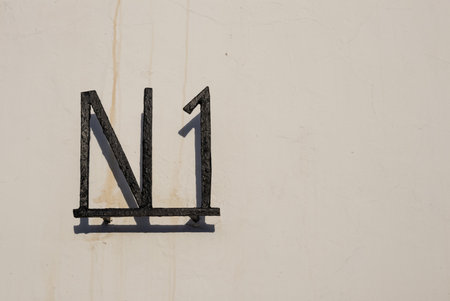 Beige facade of a house in a sunshine. Metal N 1 on the wall. Lanzarote, Canary Islands, Spain.の写真素材