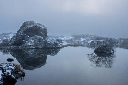 Evening at the lake. Late daylight, fog and rainy weather made the photos looking monochrome with a blue tone. Details of the small volcanic islands and rock formations. Lake Myvatn, Iceland.の写真素材