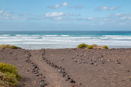 Volcanic rocks on the coast of the Atlantic ocean. Beach with a white sand. Cloudy sky in the...