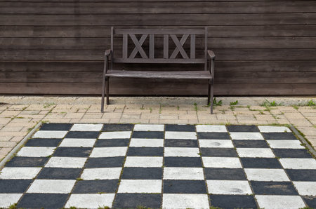Place outdoors to play chess. Chessboard and an empty wooden bench. Miniatures park where are...
