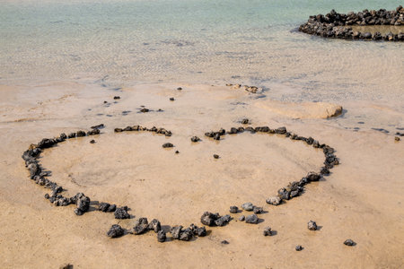 Beach in the north of the island with shallow water and a white sand, together with volcanic rocks. Outline of a heart, made of stones. Caleton Blanco, Lanzarote, Canary Islands, Spian.の写真素材