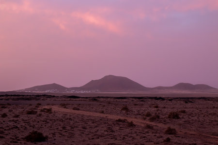 Colorful winter sunset. Volcanic land and mountains on the horizon. West coast of the island. Las Laderas, Lanzarote, Canary Islands, Spain.の写真素材
