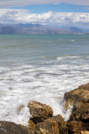 Coast protected by big rocks. Waves of the Ionic sea during a late summer day. Mountains of Albania...