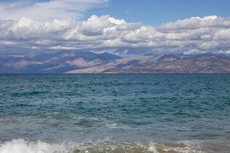 Blue water of the Ionian sea in the north-east part of the island. Mountains in Albania on the horizon. Blue sky with white clouds. Agios Spyridon, Corfu, Greece.の写真素材