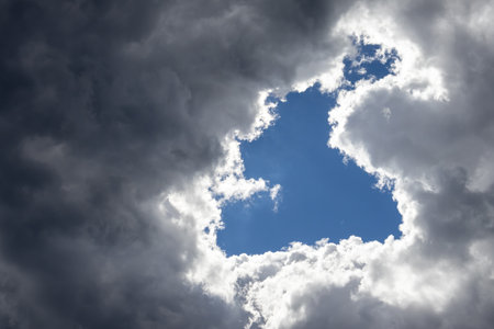 Hole in the dark stormy clouds, visible blue sky and sunshine. Corfu, Greece.の写真素材