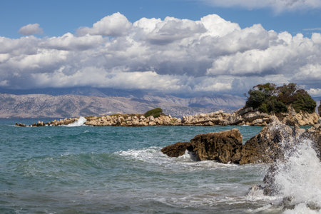 Coast of Ionian sea. Waves during a windy day in the late summer. Puddle after a storm with reflection of the sky. Blue sky with intense white clouds. North-East part of the island Corfu, Greece.の写真素材