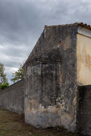 Old side wall and fence on the Saint John Monastery. Line of the roof and a white cross. Intense cloudy sky. Sidari, Corfu, Greece.の写真素材