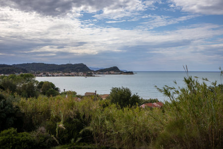 Wild vegetation on the coast of the island. View on the Ionic sea and town Sidari. Blue sky with...