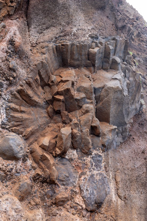 Details of the natural texture and structure of a volcanic rock, creating a cliff at the coast of...