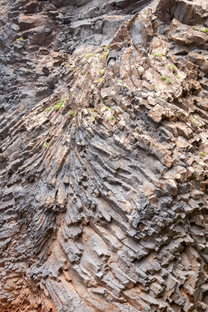 Details of the natural texture and structure of a volcanic rock, creating a cliff at the coast of...