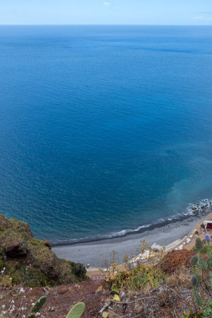 View on the calm water of Atlantic ocean from a mountain on the coast. Blue sky with white clouds in the spring. Canico, Madeira, Portugal.の写真素材