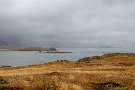 Autumn nature with a water of a fjord Foraging-Hvalfjordur. Intense cloudy sky and a fog. Place with hot springs. Hvammsvik, west Iceland.の写真素材