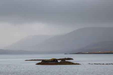 Autumn nature with a water of a fjord Foraging-Hvalfjordur. Intense cloudy sky and a fog. Place with hot springs. Hvammsvik, west Iceland.の写真素材