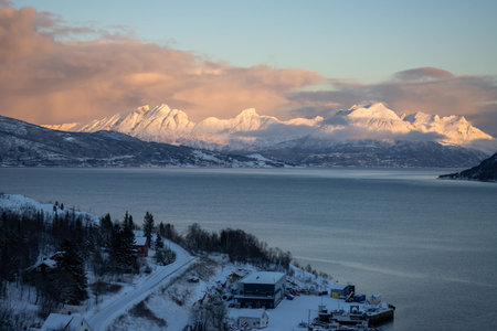 Mountains lined by calm water of the Norwegian sea. Colorful clouds in the surise/sunset of a short...