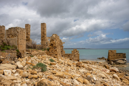 Ruins of the former tuna factory, built on the coast of the Mediterranean sea. All details remaining are made of stone. Cloudy sky in the spring. Avola, Sicily, Italy.の写真素材