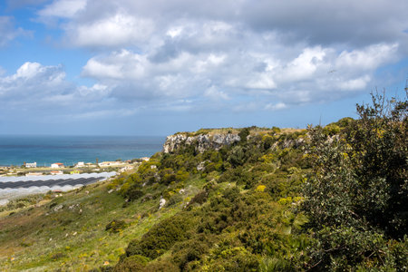 Agricultural part of the mediterranean sea with many glasshouses. Water of the sea in the background. Blue sky with white clouds in the spring. Torrefano, Sicily, Italy.の写真素材