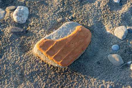 Abstract view on the beach. Dark color of the sand. Washed out stone and brick. Everything with a golden color touch during sunset. Spadafora, Sicily, Italy.の写真素材
