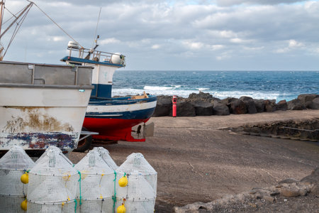 Two older color boats, parking on the coast of the Atlantic ocean. Fishing baskets. Cloudy sky in...