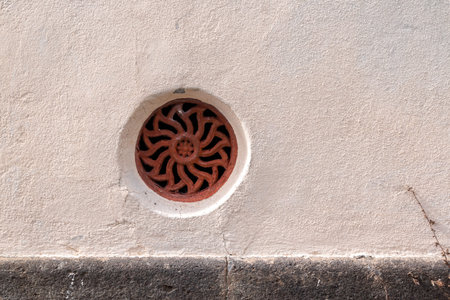 Rose facade of the Saint Martin Church (Igreja de Sao Martinho). Red aeration grate in a shape of a...