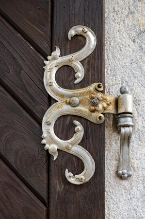 Detail of historical silver colored forging on the heavy dark brown wooden gate. Church of Assumption of Virgin Mary, Kajov, Czech Republic.の写真素材