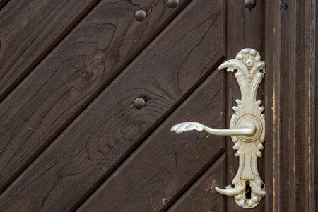 Detail of historical silver colored handle on the heavy dark brown wooden gate. Church of Assumption of Virgin Mary, Kajorv, Czech repbulic.の写真素材